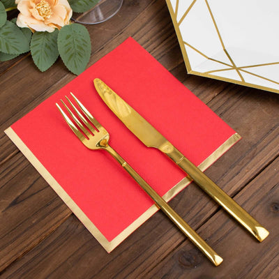 Gold cutlery set on a red napkin with a geometric plate backdrop.