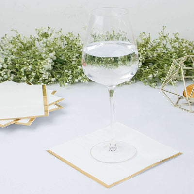 Clear glass of water on a gold-trimmed coaster with greenery in the background.