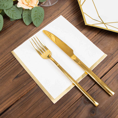 Gold fork and knife on a white napkin, styled on a wooden table.