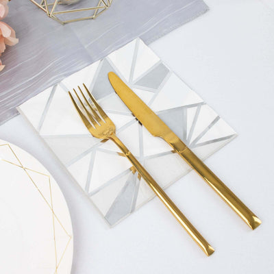 Gold cutlery on a geometric patterned plate setting.