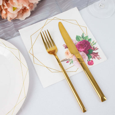 Gold fork and knife on decorative napkin with floral design.