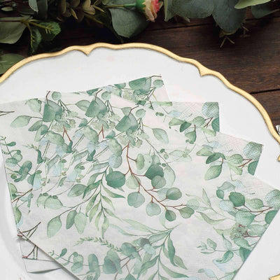 Floral-patterned napkins featuring green eucalyptus leaves on a decorative plate.