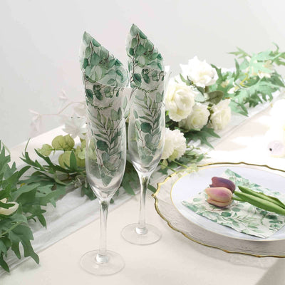 Elegant champagne flutes with green leaf napkins on a beautifully set table.