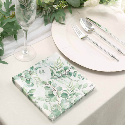Floral-patterned paper napkin on a table with cutlery and glassware.