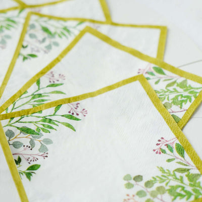 Decorative paper napkins featuring botanical prints and a yellow border.
