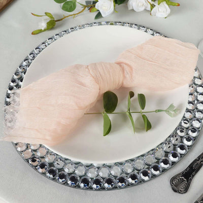 Elegant pink napkin tied with greenery on a decorative plate.