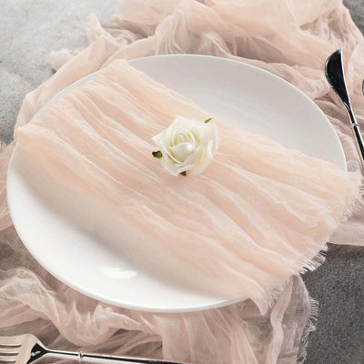 Soft pink linen napkin on a white plate with a decorative rose.