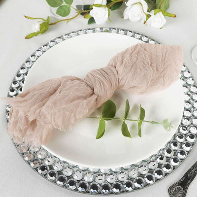 Elegant pink linen napkin styled on a decorative plate with greenery accents.