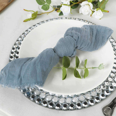 Blue linen napkin elegantly tied on a decorative plate with greenery accent.
