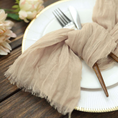 Elegant beige scarf tied around cutlery on a decorative plate.