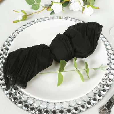 Black crinkled napkin elegantly displayed on a decorative plate with greenery.