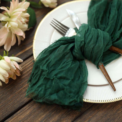 Green linen napkin elegantly tied around a plate with cutlery and flowers.