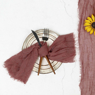 Rustic table setting with a mauve linen napkin, plate, and utensils.