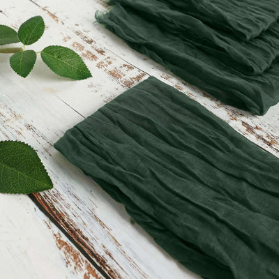 Green crinkled fabric laid out on a rustic wooden surface with leaves.