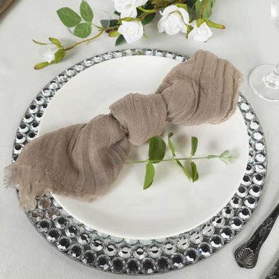 Elegant taupe scarf styled on a decorative plate with greenery accents.