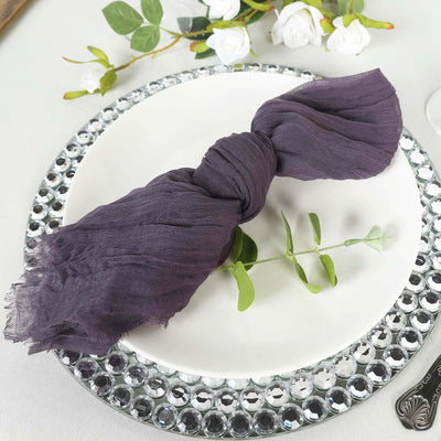 Purple linen napkin elegantly tied on a plate with greenery, styled for dining.