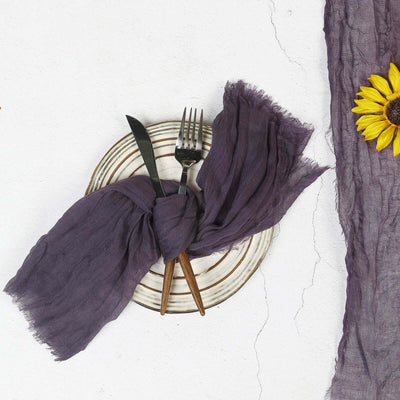 Purple linen napkin tied on a plate with cutlery and a sunflower.