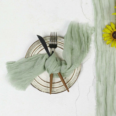 Green linen napkin tied on a plate with cutlery and sunflowers arranged around it.