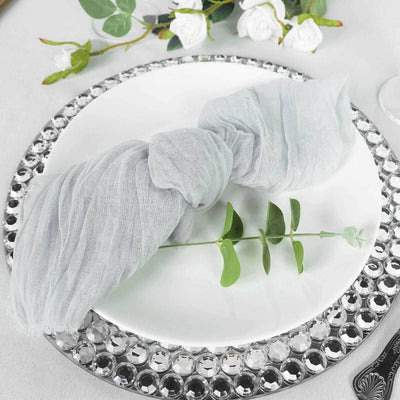 Elegant gray napkin tied with a sprig on a decorative plate.