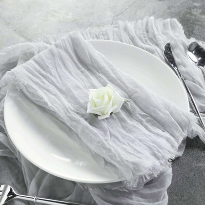 Elegant white plate with a gray napkin and a rose on a textured surface.