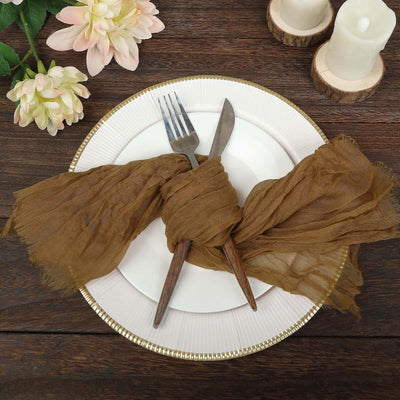 Elegant table setting with brown scarf napkin, fork, and knife on a white plate.