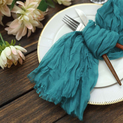 Teal table napkin elegantly styled on a white plate with cutlery and flowers.