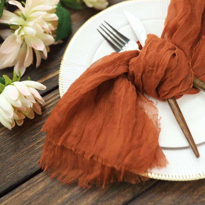 Rustic table setting with an orange scarf napkin and cutlery.