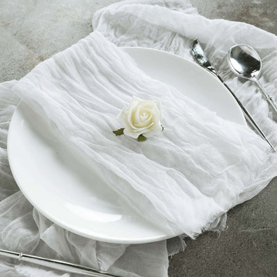 White table setting with a crinkled napkin and a rose on a plate.