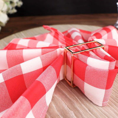 Red and white checkered napkin tied with a gold napkin ring on a wooden table.