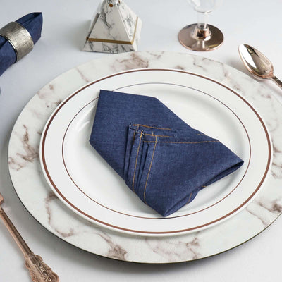 Navy blue napkin elegantly folded on a marble dinner plate.