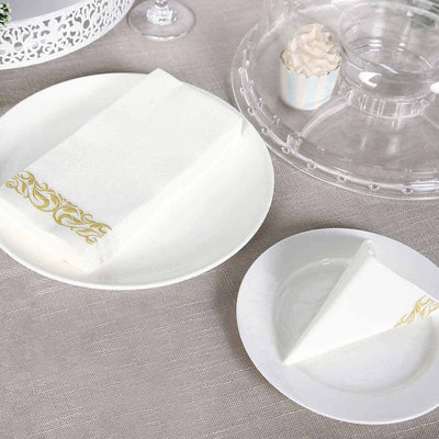 Elegant white disposable napkins with gold decorative border on plates.
