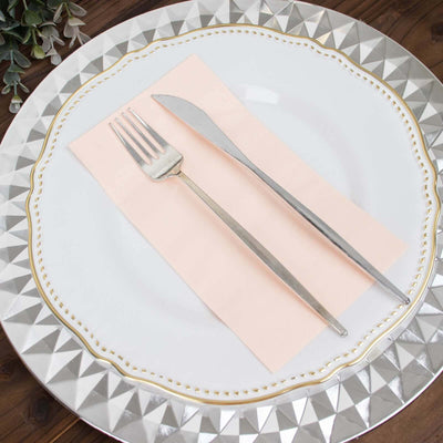 Elegant silver fork and knife on a decorative plate with a pink napkin.