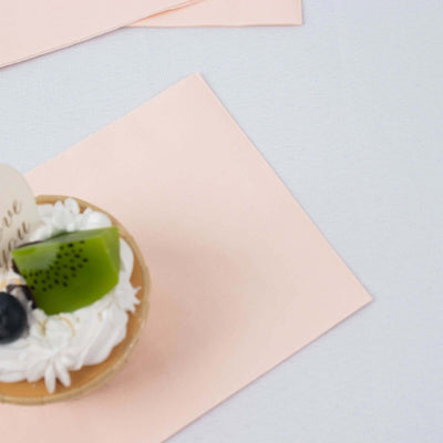 Dessert cup with whipped cream, kiwi, and blueberry on a pink napkin.