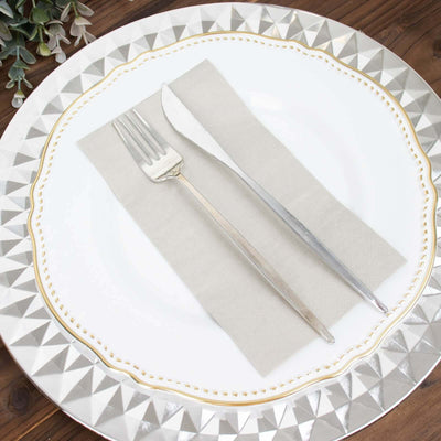 Elegant silver fork and knife on a decorative plate with a neutral napkin.