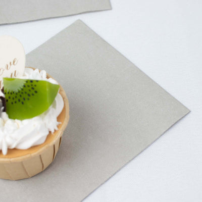 Cupcake topped with cream and fruit on a grey napkin.
