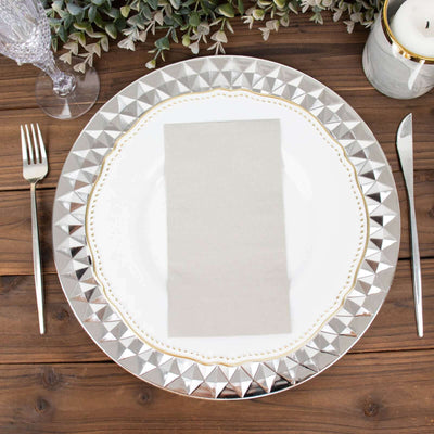 Elegant silver charger plate with a gray napkin, set on a rustic wooden table.