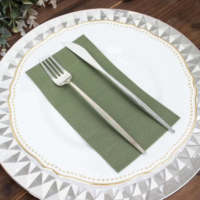 Elegant silver fork and knife on a green napkin atop a decorative plate.