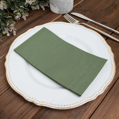 Green napkin folded on an elegant white plate with a gold rim.