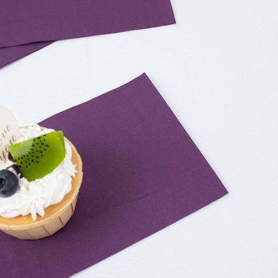 Purple napkins with a cupcake topped with cream, kiwi, and blueberries.