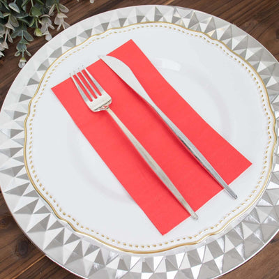 Elegant table setting with silver cutlery on a decorative plate and red napkin.