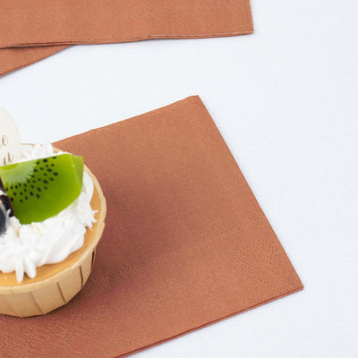 Brown napkin with a cupcake topped with fruit and cream.