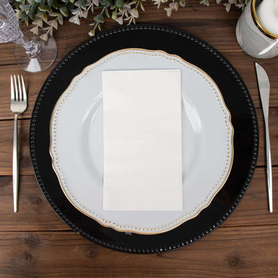 Elegant dinner plate setting with a white napkin on a wooden table.