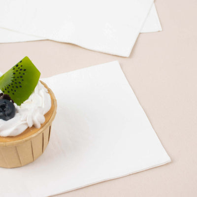 Cupcake topped with kiwi and blueberries on a napkin.