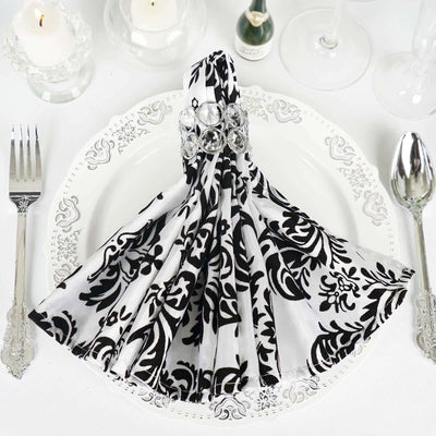 Elegant black and white patterned napkin with jeweled ring on a dining plate.