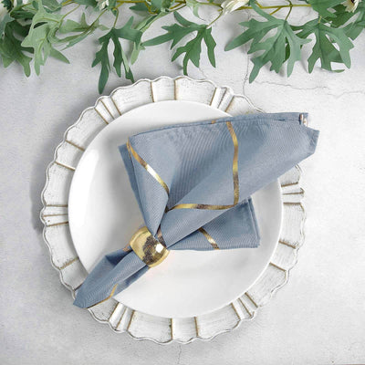 Blue patterned napkin elegantly folded on a decorative plate with greenery.