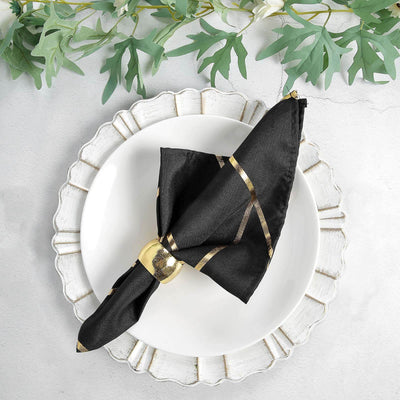 Black napkin with gold accents elegantly folded on a decorative plate.