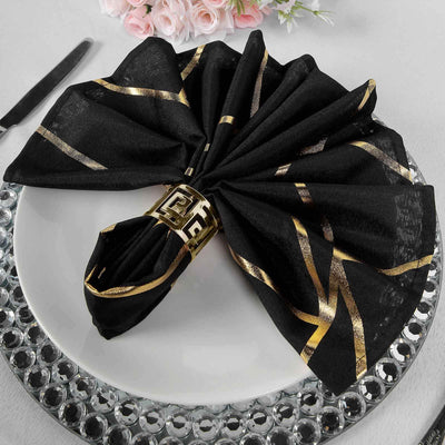 Elegant black napkin with gold accents on a decorative plate.