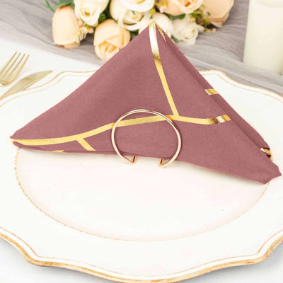 Elegant mauve napkin with gold accents, neatly folded and held by a ring on a plate.