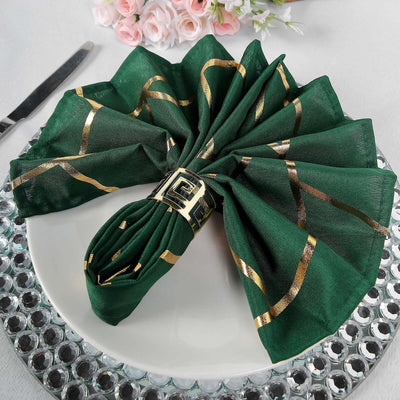Elegant green napkin with gold accents arranged on a decorative plate.