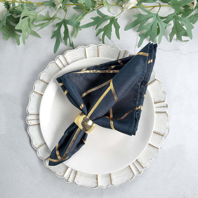 Navy blue napkin with gold stripes elegantly tied on a decorative plate.